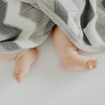 Charming view of a baby's feet under a cozy patterned blanket.